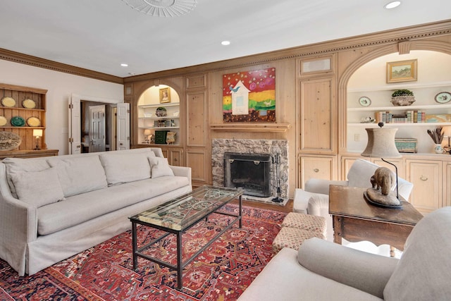 living area with built in shelves, recessed lighting, crown molding, and a premium fireplace