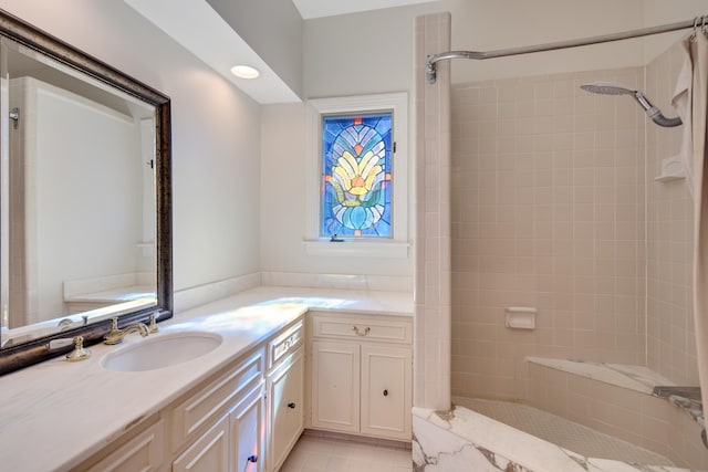 full bathroom featuring tile patterned flooring, a tile shower, and vanity