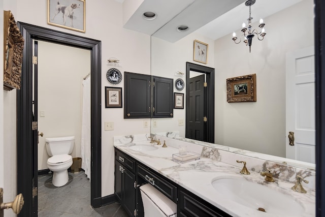 bathroom with baseboards, a sink, toilet, and double vanity