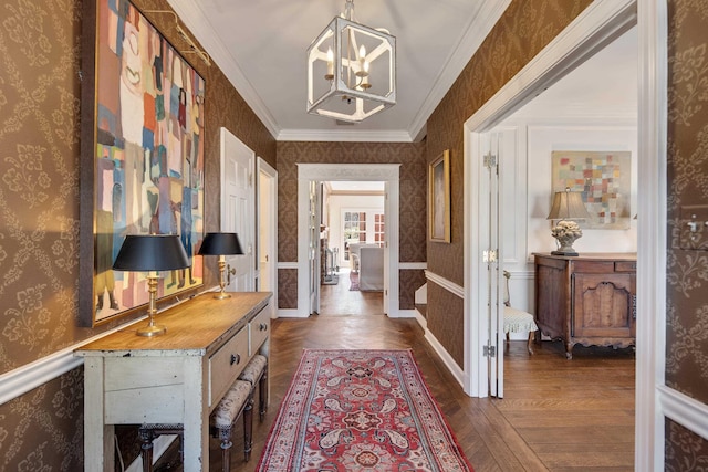 entrance foyer with wallpapered walls, wainscoting, dark wood-style flooring, an inviting chandelier, and crown molding