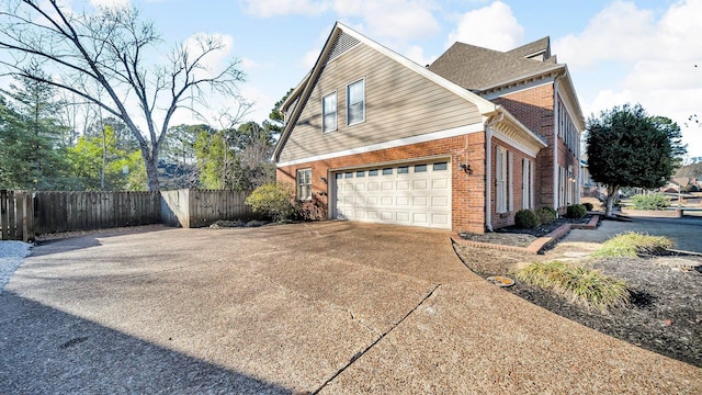 view of home's exterior with an attached garage, fence, concrete driveway, and brick siding