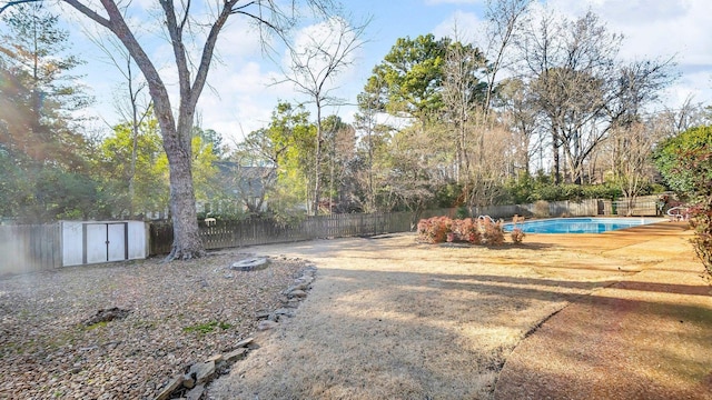 view of yard featuring a fenced backyard, an outdoor structure, a fenced in pool, and a shed