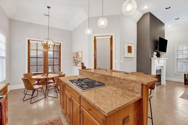 kitchen with a fireplace, stainless steel gas stovetop, decorative light fixtures, and a kitchen breakfast bar