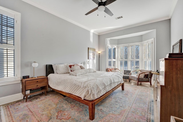 bedroom featuring ceiling fan, wood finished floors, visible vents, baseboards, and crown molding