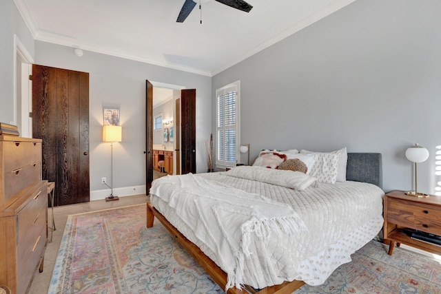 bedroom with baseboards, ensuite bath, a ceiling fan, and crown molding