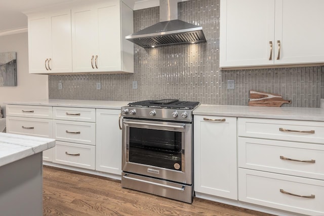 kitchen featuring white cabinets, wall chimney range hood, decorative backsplash, stainless steel gas stove, and dark wood finished floors