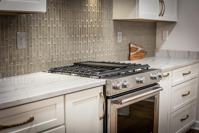 kitchen featuring white cabinets, light stone countertops, stainless steel range with gas cooktop, and decorative backsplash