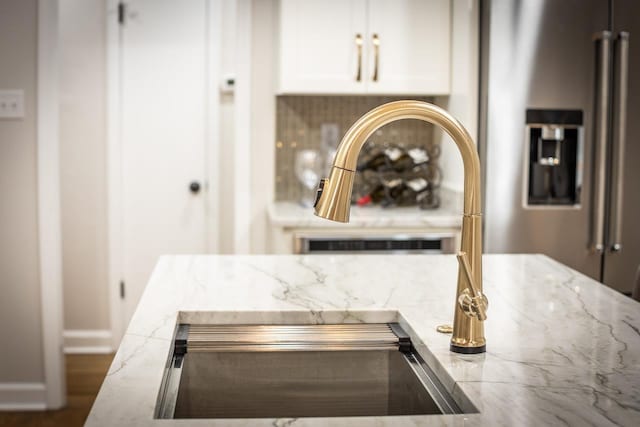 interior details with baseboards, light stone countertops, and white cabinets