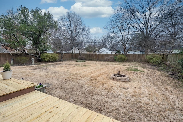 view of yard featuring a deck, an outdoor fire pit, and a fenced backyard