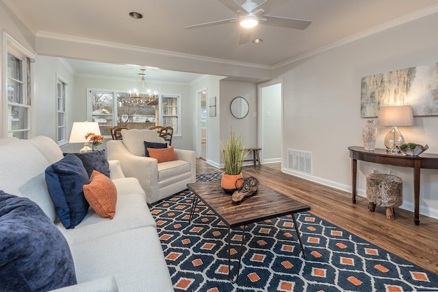 living area featuring crown molding, visible vents, wood finished floors, baseboards, and ceiling fan with notable chandelier