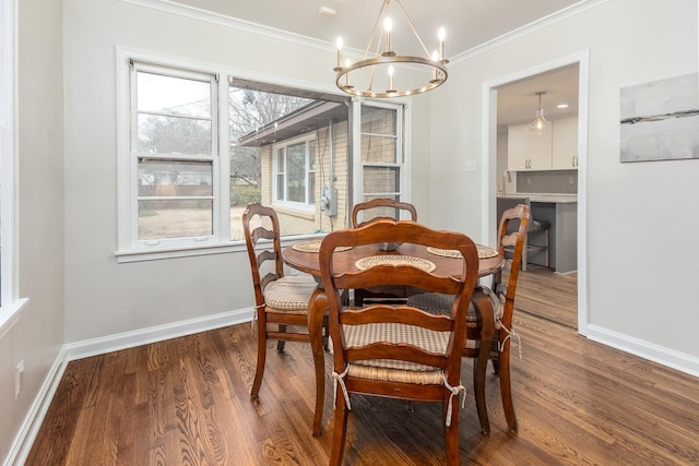 dining space featuring ornamental molding, a chandelier, baseboards, and wood finished floors