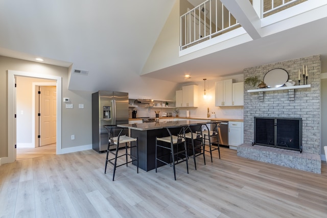 kitchen featuring open shelves, stainless steel appliances, visible vents, white cabinetry, and a kitchen breakfast bar