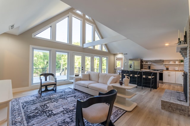 living area featuring high vaulted ceiling, visible vents, baseboards, french doors, and light wood-type flooring