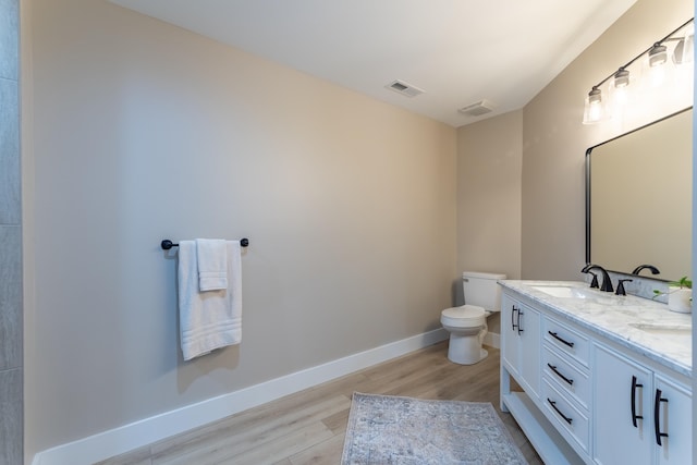 bathroom with baseboards, visible vents, toilet, wood finished floors, and a sink