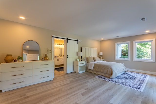 bedroom featuring a barn door, visible vents, ensuite bath, light wood-type flooring, and recessed lighting