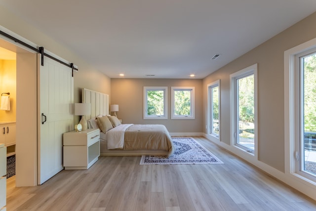 unfurnished bedroom with a barn door, recessed lighting, visible vents, baseboards, and light wood-type flooring