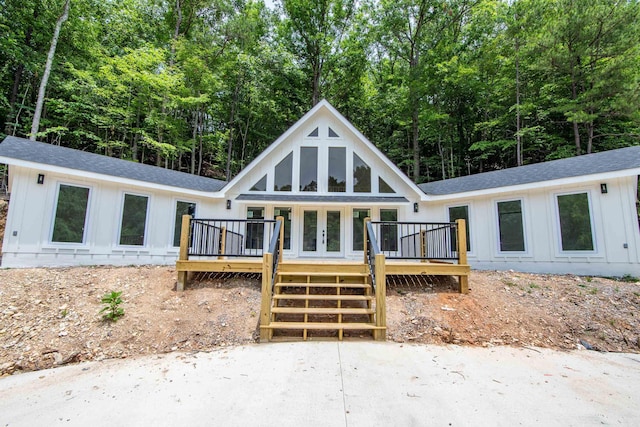 view of front of home featuring roof with shingles, french doors, board and batten siding, and a wooden deck