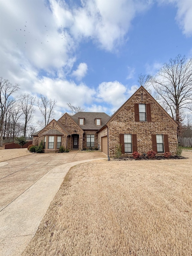 view of front of house featuring an attached garage, brick siding, a shingled roof, fence, and concrete driveway