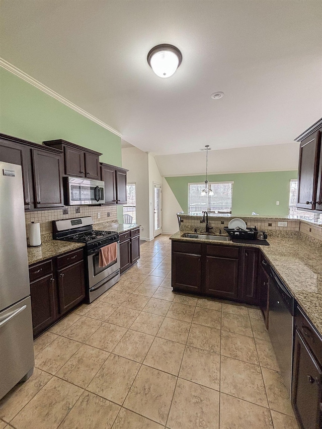 kitchen featuring stainless steel appliances, light stone counters, dark brown cabinets, and tasteful backsplash