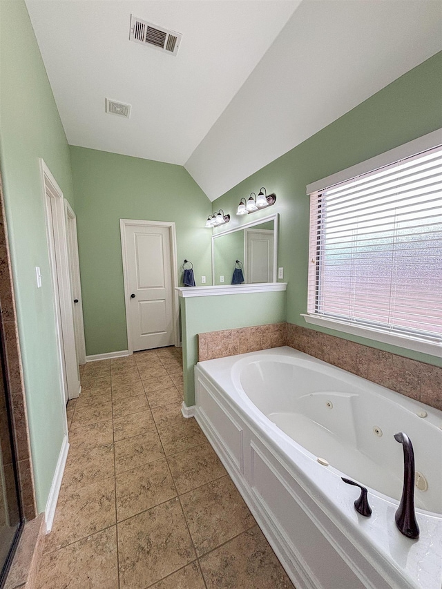 bathroom featuring visible vents, vaulted ceiling, a jetted tub, and tile patterned floors