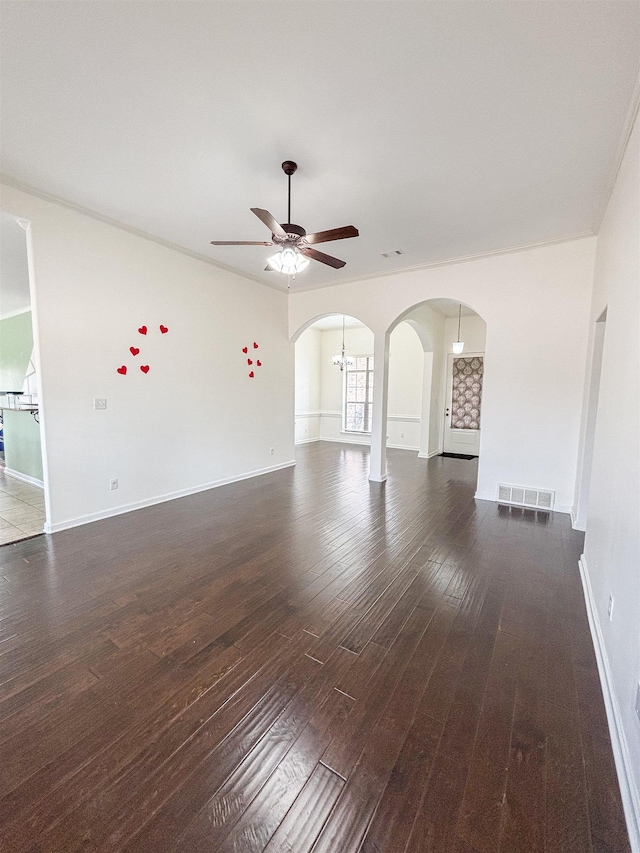 unfurnished living room featuring arched walkways, visible vents, wood finished floors, baseboards, and ceiling fan with notable chandelier