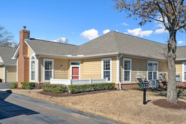 view of front of property featuring brick siding, a chimney, and roof with shingles