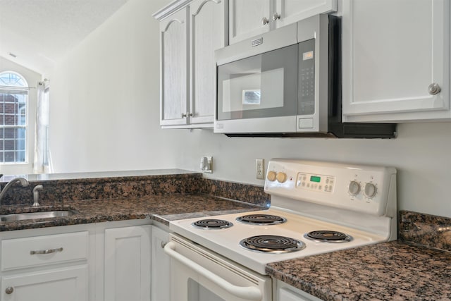 kitchen with lofted ceiling, electric range, a sink, stainless steel microwave, and dark stone countertops