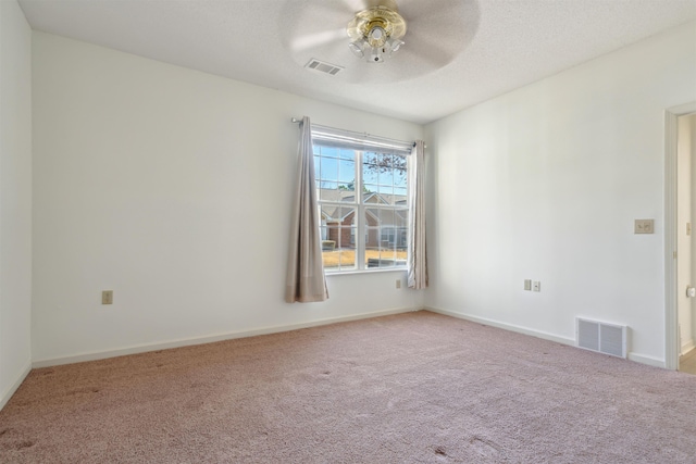 carpeted spare room featuring ceiling fan, a textured ceiling, visible vents, and baseboards