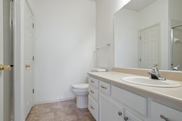 full bath featuring baseboards, a shower with door, vanity, and toilet