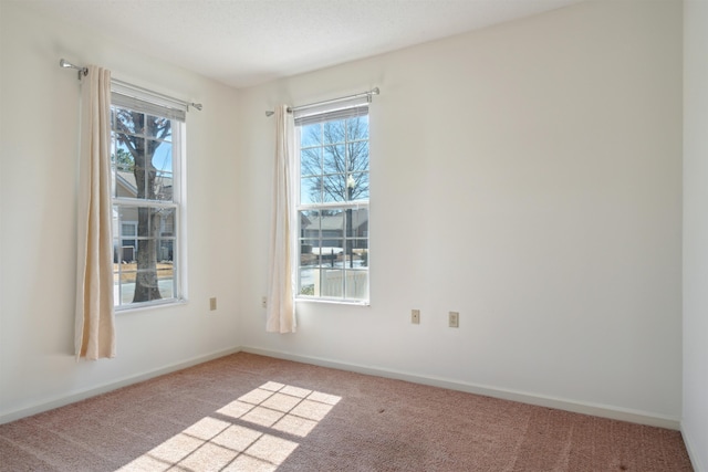 unfurnished room with carpet floors, a wealth of natural light, and baseboards