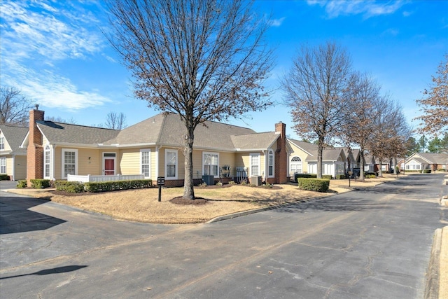 single story home with central air condition unit, a chimney, and a residential view