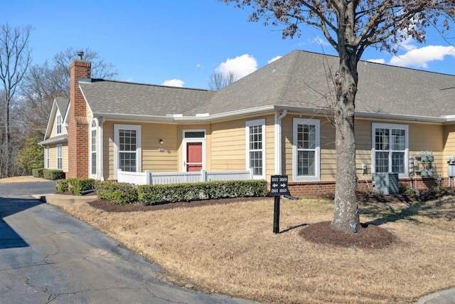 single story home with roof with shingles, brick siding, and a chimney