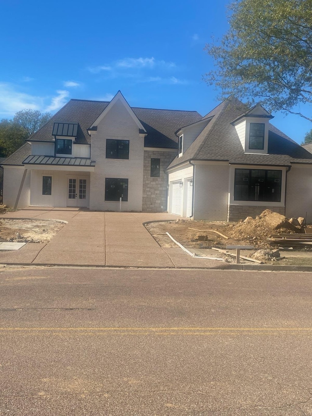 view of front facade with roof with shingles, concrete driveway, an attached garage, a standing seam roof, and metal roof