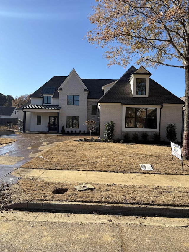 view of front of house with a standing seam roof, brick siding, and metal roof