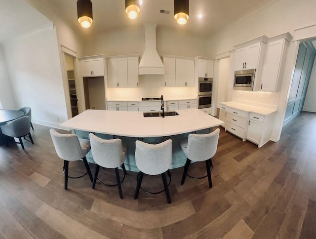 kitchen featuring a large island, appliances with stainless steel finishes, custom exhaust hood, white cabinets, and a sink