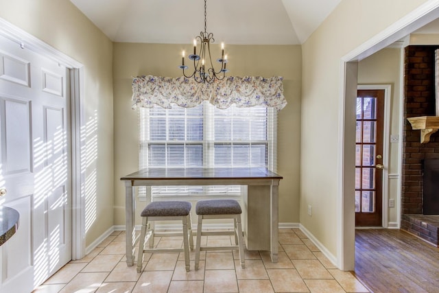 dining room featuring light tile patterned floors, plenty of natural light, a fireplace, and an inviting chandelier