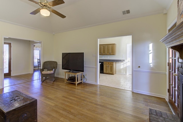 living room with light wood-style flooring, a ceiling fan, visible vents, and crown molding