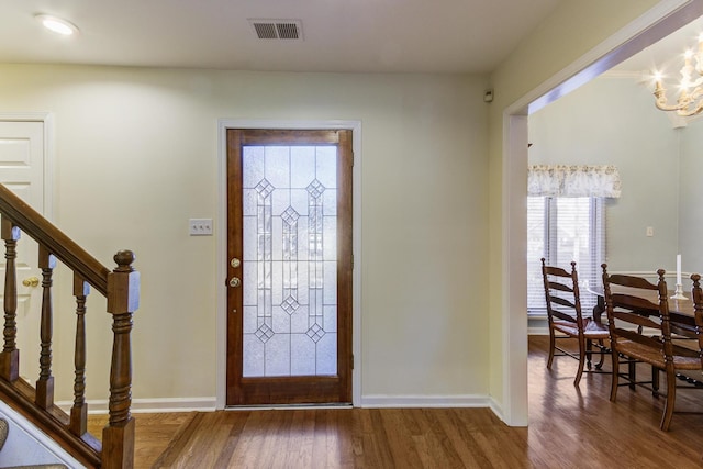 foyer featuring stairs, visible vents, baseboards, and wood finished floors