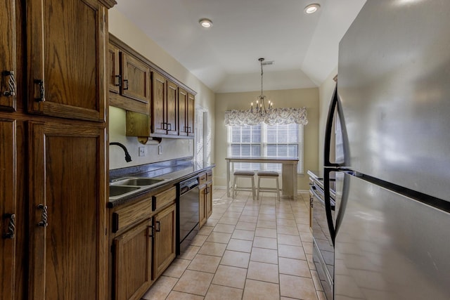 kitchen featuring light tile patterned floors, dishwasher, dark countertops, freestanding refrigerator, and a sink