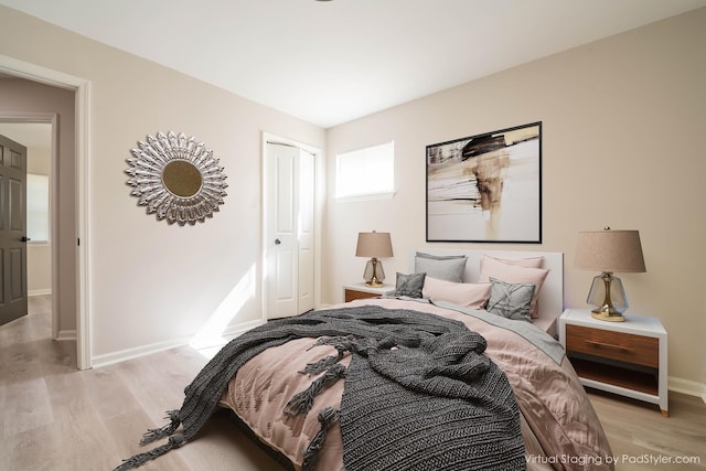 bedroom with light wood-style flooring, baseboards, and a closet