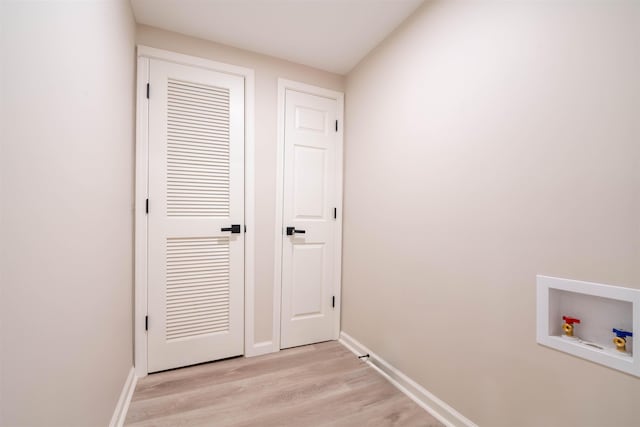 interior space featuring washer hookup, laundry area, baseboards, and light wood finished floors