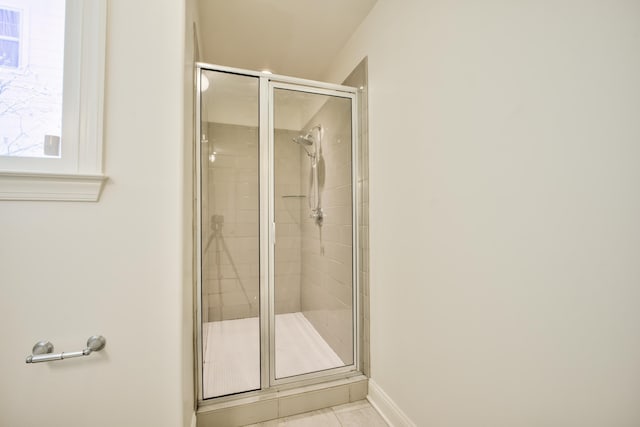 full bath with a stall shower, tile patterned flooring, and baseboards