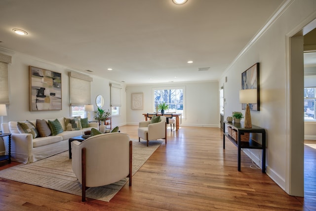 living room with light wood finished floors, visible vents, baseboards, ornamental molding, and recessed lighting