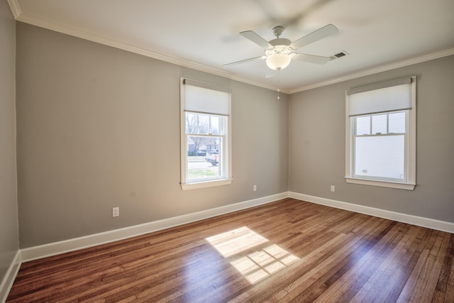 unfurnished room featuring visible vents, ornamental molding, ceiling fan, baseboards, and hardwood / wood-style flooring