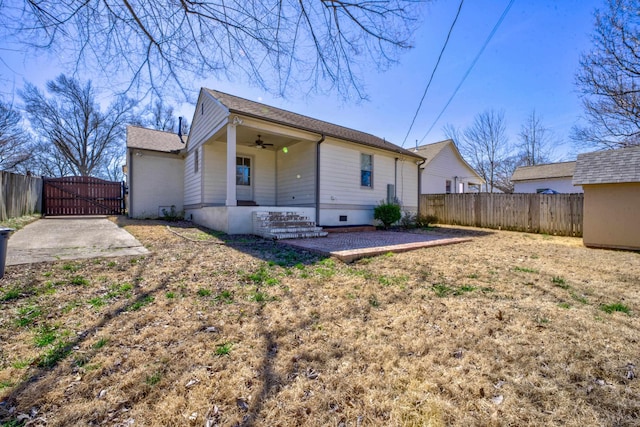 back of house with ceiling fan, fence, and a gate