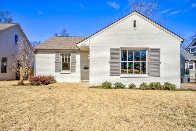 back of property featuring brick siding, a lawn, and a shingled roof