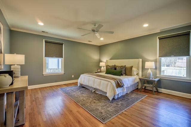 bedroom featuring multiple windows, crown molding, baseboards, and wood finished floors