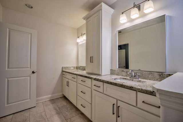 full bathroom featuring double vanity, a sink, and baseboards