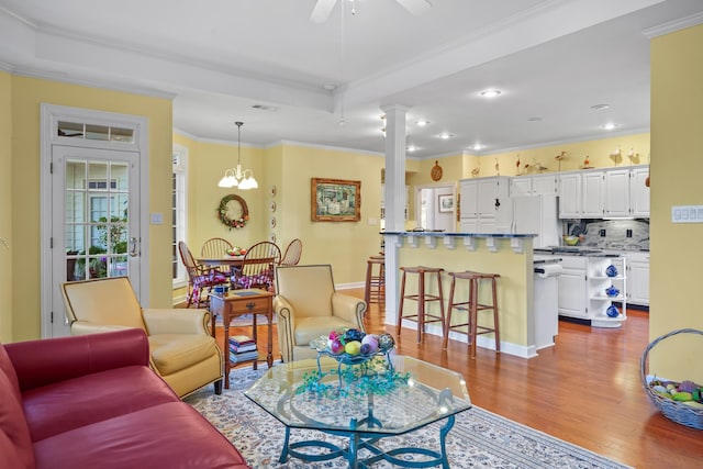 living area featuring decorative columns, visible vents, ornamental molding, a ceiling fan, and wood finished floors