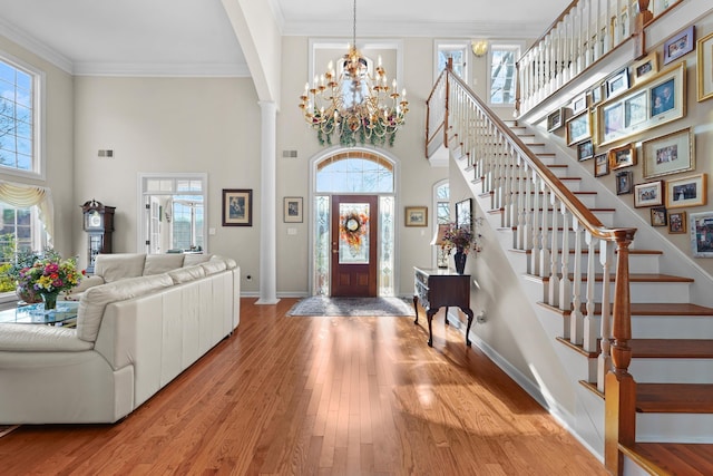 entryway with light wood finished floors, baseboards, stairway, and ornamental molding